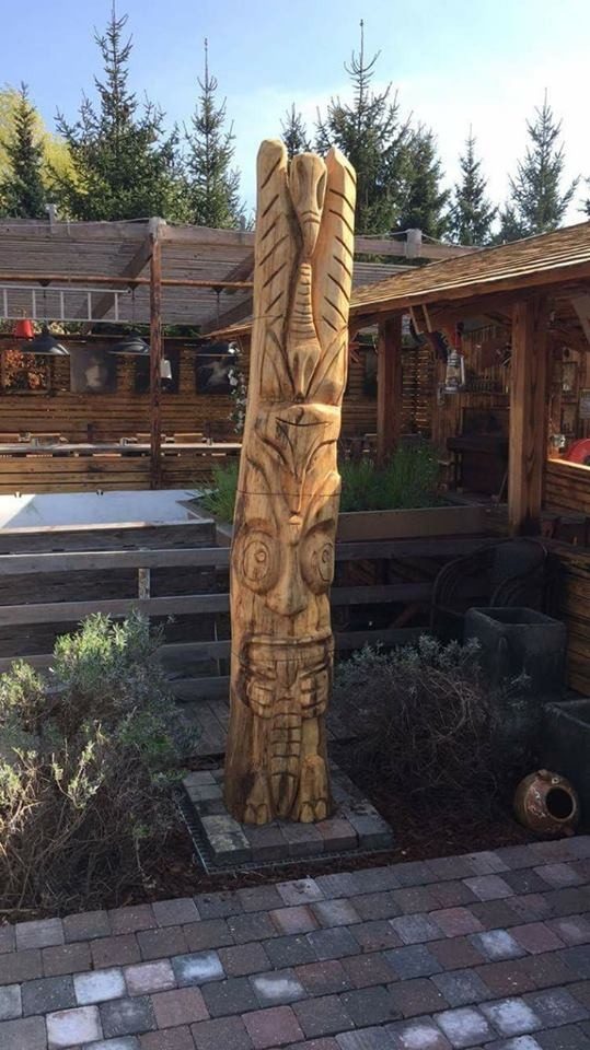 Grand totem en bois sculpté dressé sur la terrasse d'un restaurant.