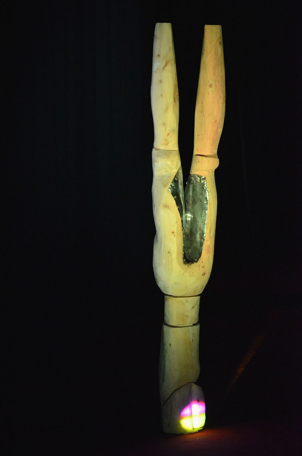 Totem clair en deux branches, incrusté de métal, éclairé dans le noir.